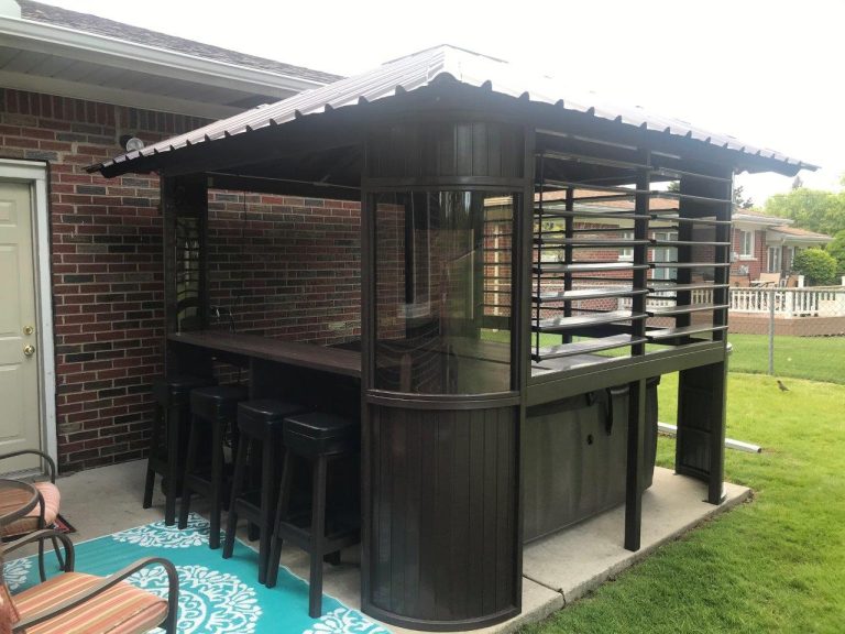 Outdoor bar with a covered roof, stools, and a patio rug next to a brick house.