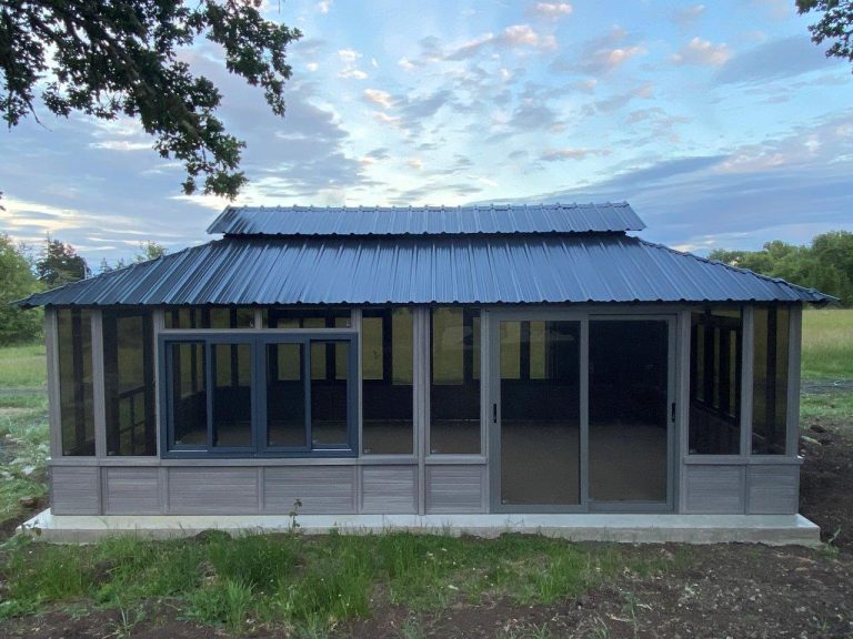 Metal-roofed, screened gazebo in a field under a partly cloudy sky.