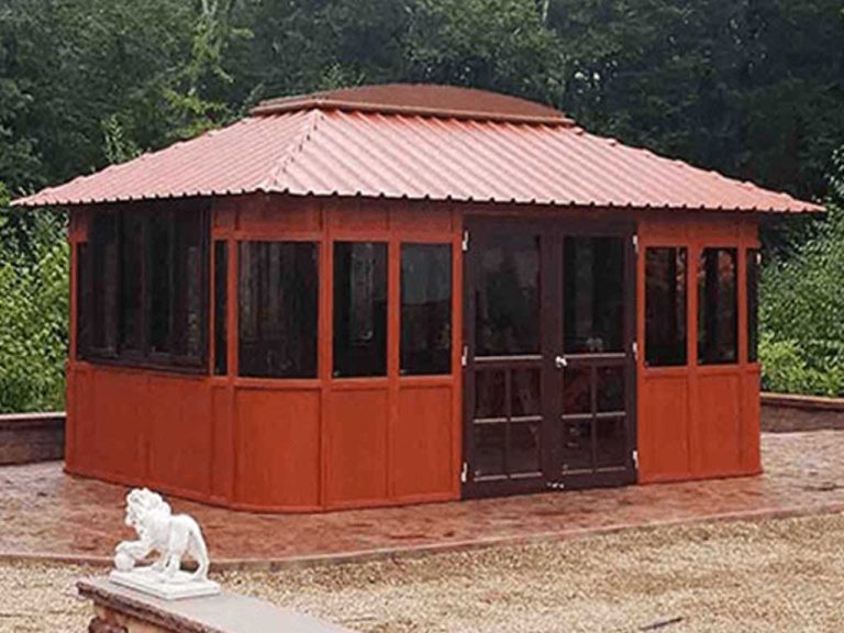 Wooden gazebo with a red roof and dark windows, surrounded by trees, with a stone lion statue in the foreground.