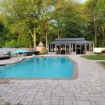 Backyard with a swimming pool, patio furniture, gazebo, and surrounded by trees and a fence.
