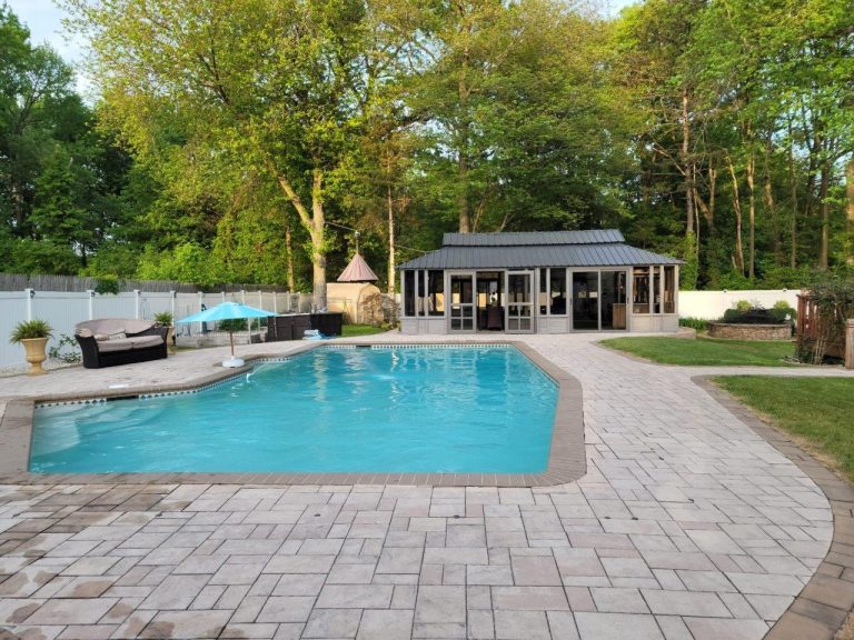 Backyard with a swimming pool, patio furniture, gazebo, and surrounded by trees and a fence.