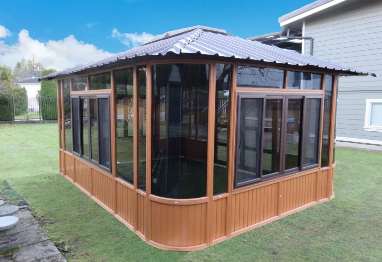 Wooden gazebo with large windows on green grass, under a blue sky.