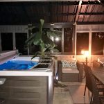 Indoor hot tub area with seating, table, and ambient lighting at night.