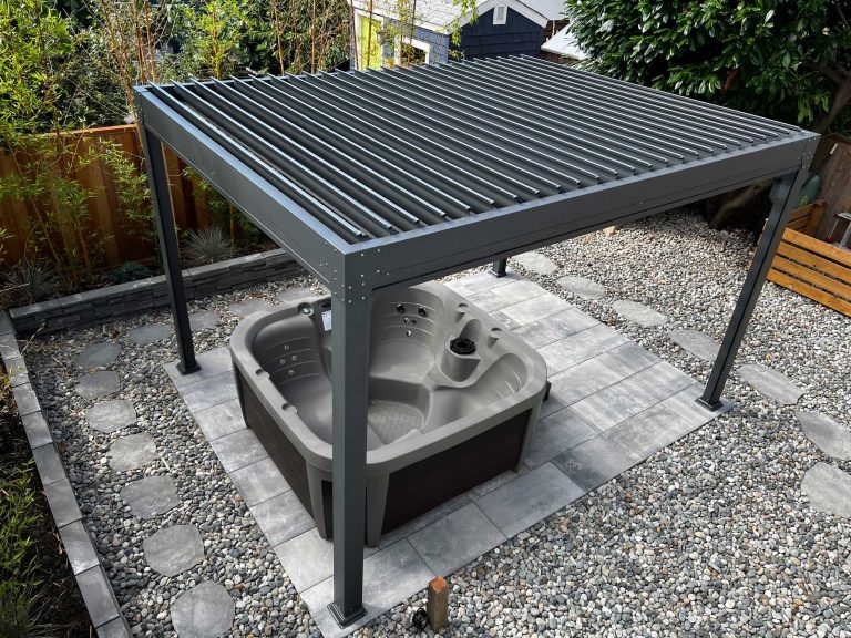 Outdoor hot tub under a metal pergola, surrounded by gravel, tiles, and a wooden fence.