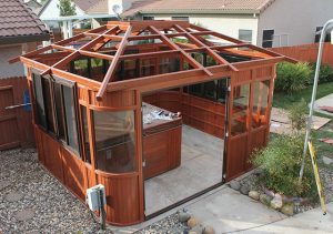 Wooden gazebo under construction with open frame roof in a garden setting.