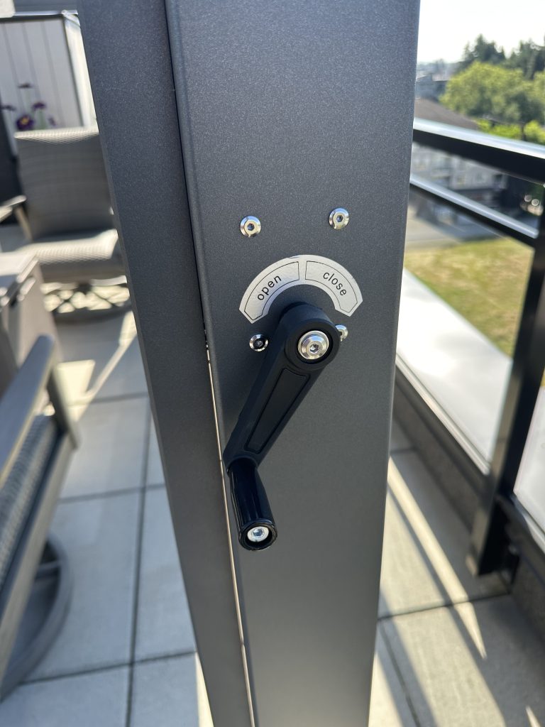 Close-up of a gray window or door handle with "open" and "close" labels on a modern balcony.