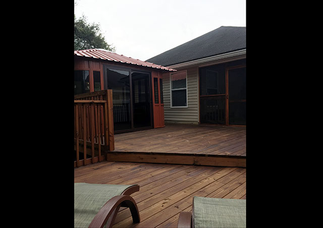Wooden deck with steps, featuring a small gazebo and screened porch attached to a house.