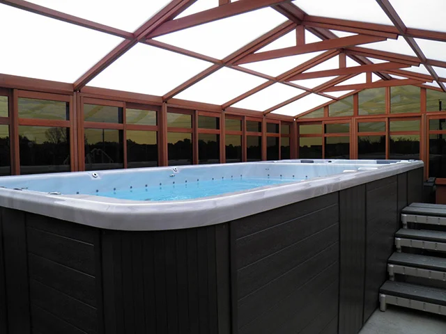 Indoor pool with wooden framing, skylight roof, and steps leading to the water.