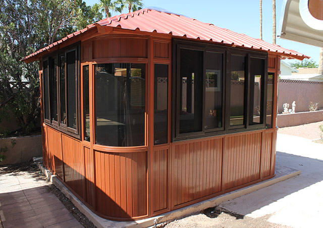 Aspen 12x12 hot tub gazebo with large dark-tinted windows and a red metal roof on a concrete base